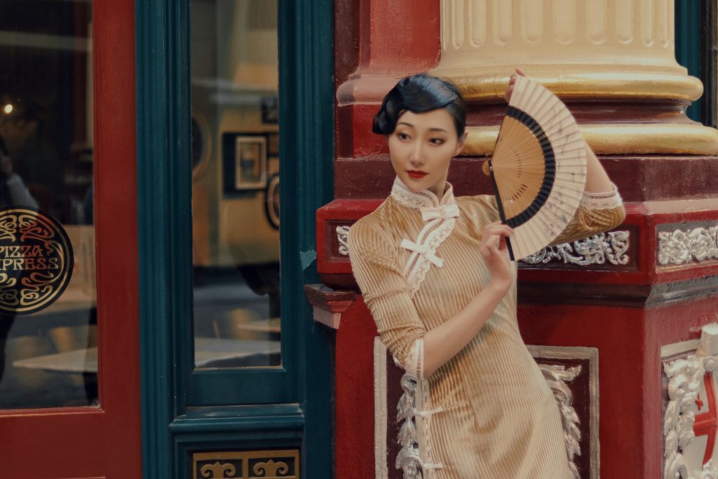 A Chinese performer wearing Shanghai-style dress with a traditional folding fan